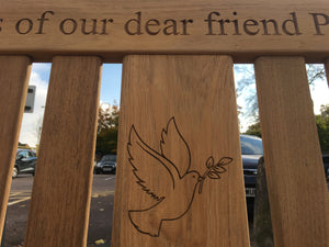 memorial bench with a dove, carrying an olive branch in its beak, carved into the wood - 4mb4578